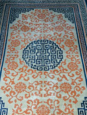 an orange and blue oriental rug on a wooden floor
