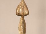 a gold sculpture on a glass table with a white wall in the background