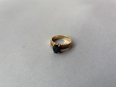 une image d'une bague en or avec une pierre bleue