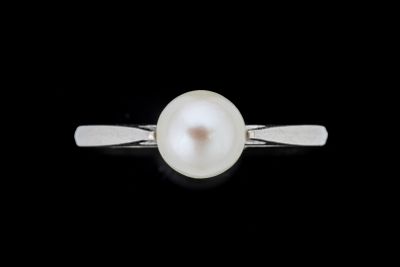 une image représentant une bague en perle blanche sur fond noir