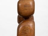 wooden sculpture of a man and a woman on a white pedestal