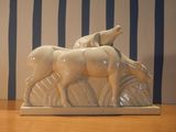 une sculpture en céramique représentant deux chevaux et un chien, posée sur une table