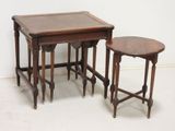 two tables and a stool in a room with a wall in the background