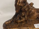 a bronze statue of a dog and a cat laying on a rock