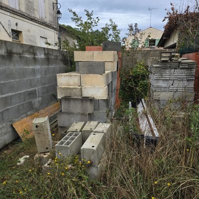 un tas de parpaings dans une cour, à côté d'un immeuble