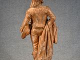statue of a man with a hat and jacket holding a bag