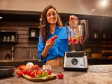 a woman that is making some food in a blender