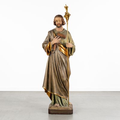 a statue of jesus holding a staff in a white room