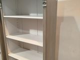 two open shelves in a room with white walls and wood flooring