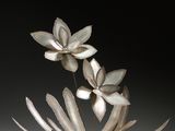 une sculpture métallique représentant des fleurs dans un vase posé sur une table