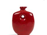 a red vase with a hole in the middle of it
