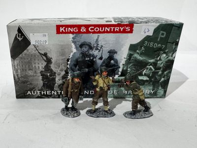 deux figurines représentant des hommes en uniforme militaire se tiennent à côté d'une boîte