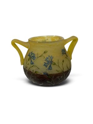 un vase jaune orné de fleurs bleues, posé sur une surface blanche