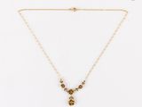 un collier en or avec un pendentif en forme de fleur, monté sur une chaîne en or