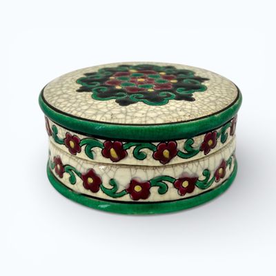 a small round box with a flower design on it