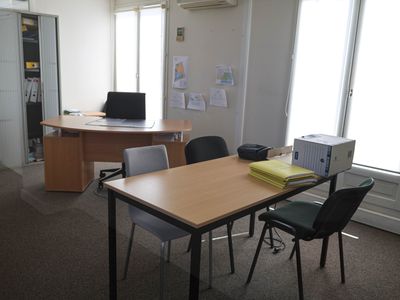 tables and chairs in an office with a computer on the desk