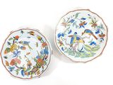 two plates with birds and flowers on them on a white surface