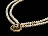 a close up of a pearl necklace with a heart charm