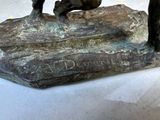 a bronze statue of a dog and a cat on a rock
