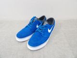 des baskets bleues et blanches à semelles blanches posées sur une surface grise
