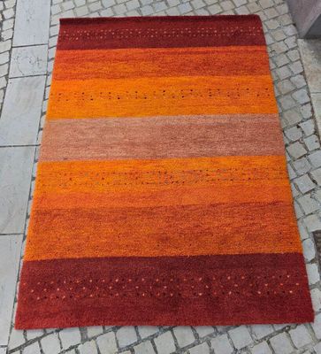 un tapis rayé orange et rouge posé sur un sol en briques