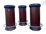 trois socles en bois avec des plateaux en cuir noir et une base en métal