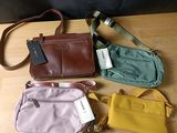 quatre sacs à main posés sur une table en bois, avec des étiquettes accrochées dessus