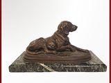 statue d'un chien couché sur un socle en marbre, encadrée d'un cadre rouge