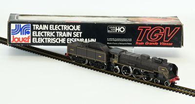 un petit train qui se trouve sur les rails, à côté d'une boîte