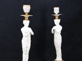 pair of white and gold candlesticks with statues on them