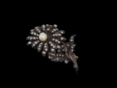 un gros plan d'une broche ornée de perles et de diamants