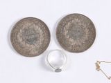 three silver coins and a silver ring are on a white surface