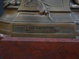 a bronze statue of a woman sitting on top of a table