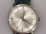 a silver watch on a green strap on a white surface