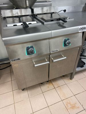 stainless steel counter top with two deep fryers on each side of it