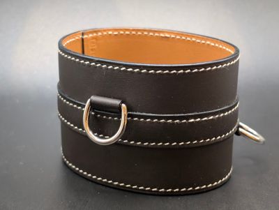 brown leather cuff bracelet with a silver ring on a black surface
