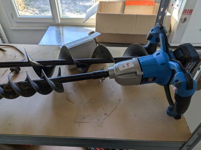 a blue and black drill on a workbench in a room