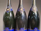 trois bouteilles de champagne posées sur une table l'une à côté de l'autre