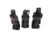 three black figurines of asian figures on a white surface