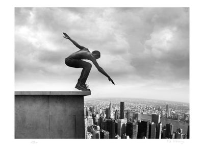 photographie en noir et blanc d'un skateur en train de réaliser une figure sur un rebord devant un paysage urbain