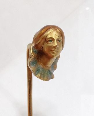 sculpture représentant une tête de femme fixée sur un bâton, posée sur une surface blanche