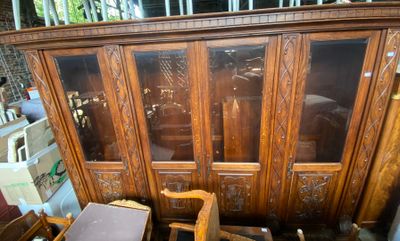 une armoire en bois avec des portes vitrées, devant laquelle se trouve une chaise