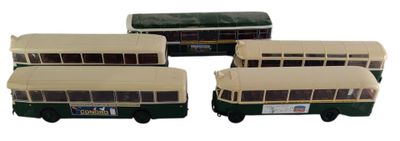 quatre bus miniatures sont alignés en rang sur une surface blanche