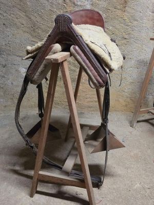 une selle de cheval posée sur un support en bois dans une pièce