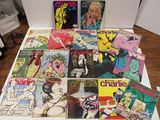 a lot of comic books on a table with a bottle of wine in the background