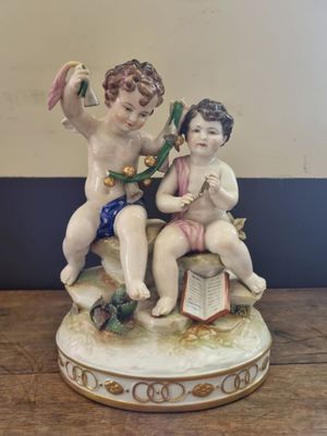 a figurine of two children sitting on top of a book