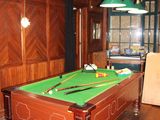 une table de billard au milieu d'une pièce, recouverte d'un tapis vert