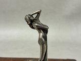 an antique silver figurine of a woman holding a baseball bat