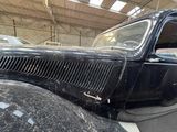 a black car parked in a garage with other cars in the background