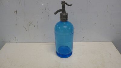 une bouteille bleue munie d'une pompe noire, posée sur une table blanche